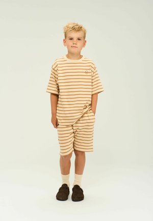 Beige och ljusbrun randig T-shirt och shorts-set. Mjuk textur, lös passform, korta ärmar, med en liten logotyp på t-shirten. Bruna skor.