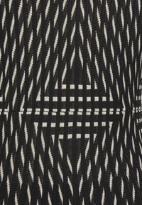 Czarna i biała tkana tkanina z wzorem w zygzak oraz poziomymi paskami, tworząca teksturowany, geometryczny design.