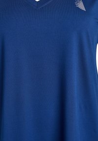 Blå V-ringad t-shirt i slätt material. Har ett texturerat mönster på övre vänstra sidan, med rak skärning och korta ärmar.