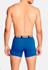 Blaue Boxershorts aus weichem Stoff mit einem schwarzen elastischen Bund und weißer "PUMA"-Markierung. Einfaches Design mit enger Passform.
