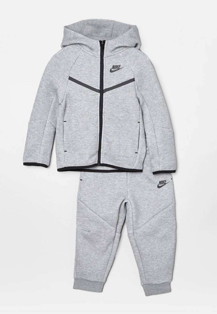 Grauer Reißverschluss-Hoodie mit schwarzen Akzenten und Logo, kombiniert mit passenden grauen Jogginghosen in tapered Fit und mit elastischen Bündchen.