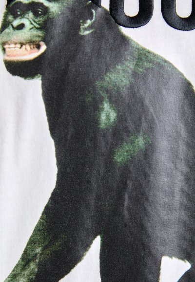 Sorte og hvide stof med et grafisk motiv af en gorillas profil fra siden. Designet fremhæver detaljer som ansigtstræk og tekstureret pels.