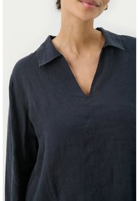 Navy linen shirt featuring a collared neckline, long sleeves, and a V-shaped placket, with a soft, textured finish.