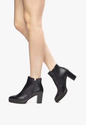Black ankle boots made of smooth leather with a chunky heel, side zippers, and minimalist design, showcasing a clean and modern silhouette.
