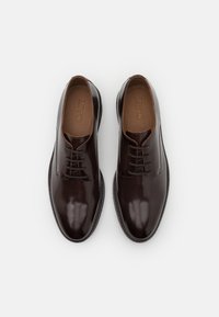 Brune skinn dressko med en blank finish, rund tå og tradisjonell snøring. Solid svart gummisåle.