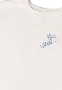 Camiseta de algodón crema con cuello redondo, con gráficos impresos en azul claro de una mano y el texto "O'Neill" en el área del pecho izquierdo.