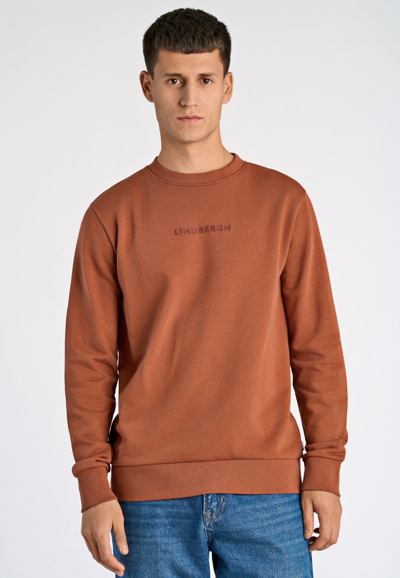 Felpa marrone con colletto a girocollo, maniche lunghe e polsini a coste. La parte anteriore presenta un ricamo "LINDBERGH" in una tonalità più scura.