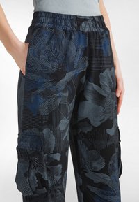 Sorte cargobukser med blåt blomsterdesign og tekstureret mønster, med elastisk taljebånd og sidelommer.