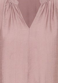 Tissu texturé rose doux avec un col en V froncé et une couture verticale au centre devant d'un chemisier ou d'une robe.