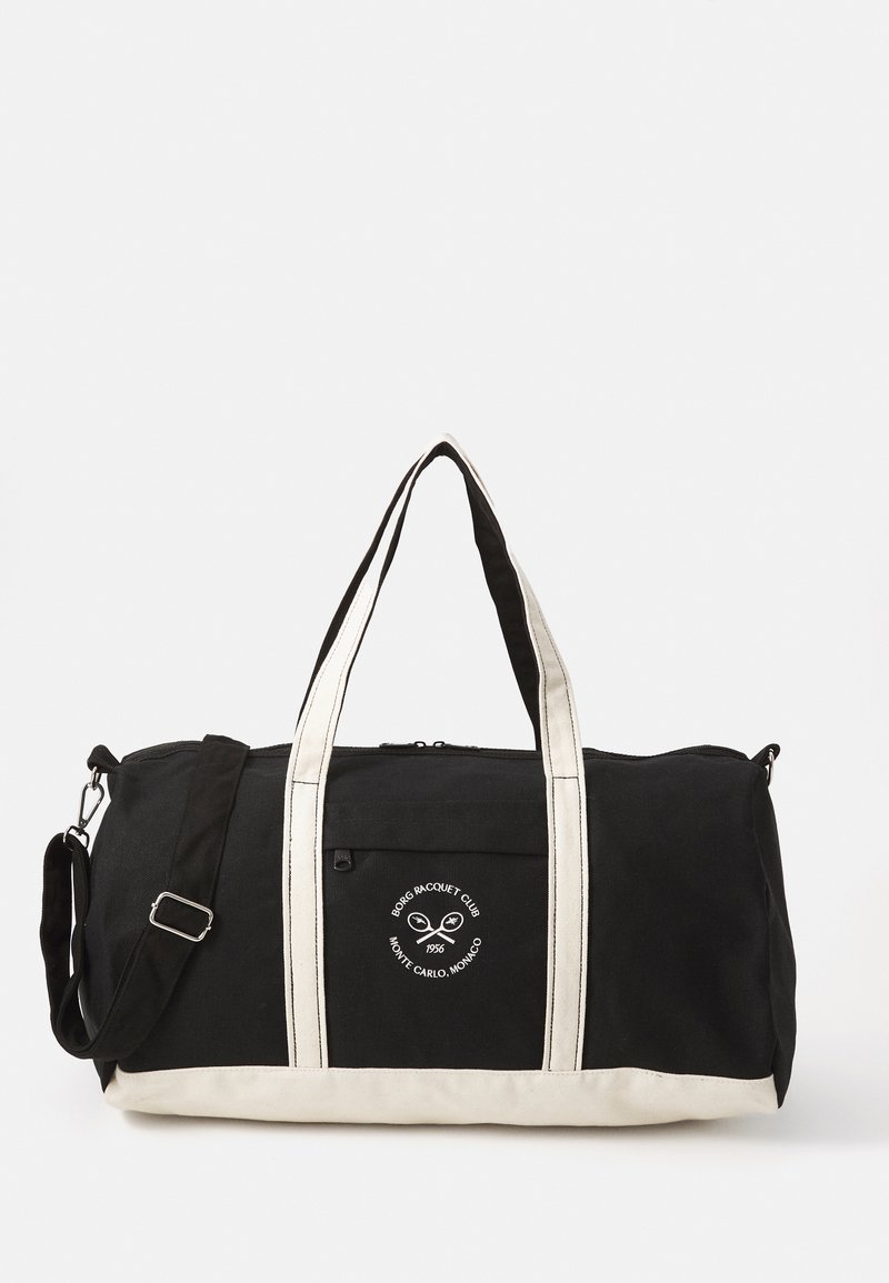 Fekete sporttáska krém szalagokkal és logóval; tartós anyagból készült, cipzáros záródással és oldalzsebbel a további tárolás érdekében.