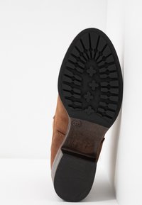Brown suede boot with a textured black rubber sole. Flat heel, rounded front, and size indicator "37" on the bottom. Clean design.