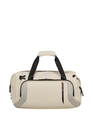 Beige Duffel-Tasche mit schwarzen Griffen, vorderer Reißverschlusstasche und strukturierten Eckakzenten auf weißem Hintergrund.