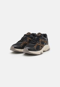 Chaussures de sport noires avec un design en imprimé léopard sur les côtés, dotées de matériaux en maille et synthétiques, de lacets texturés et d'une semelle beige.