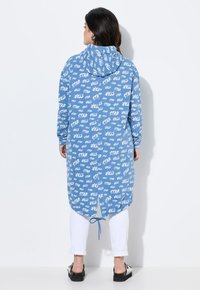 Ljust blå huva klänning med vitt textmönster. Har långa ärmar, en krökt fåll och justerbar dragsko bak.