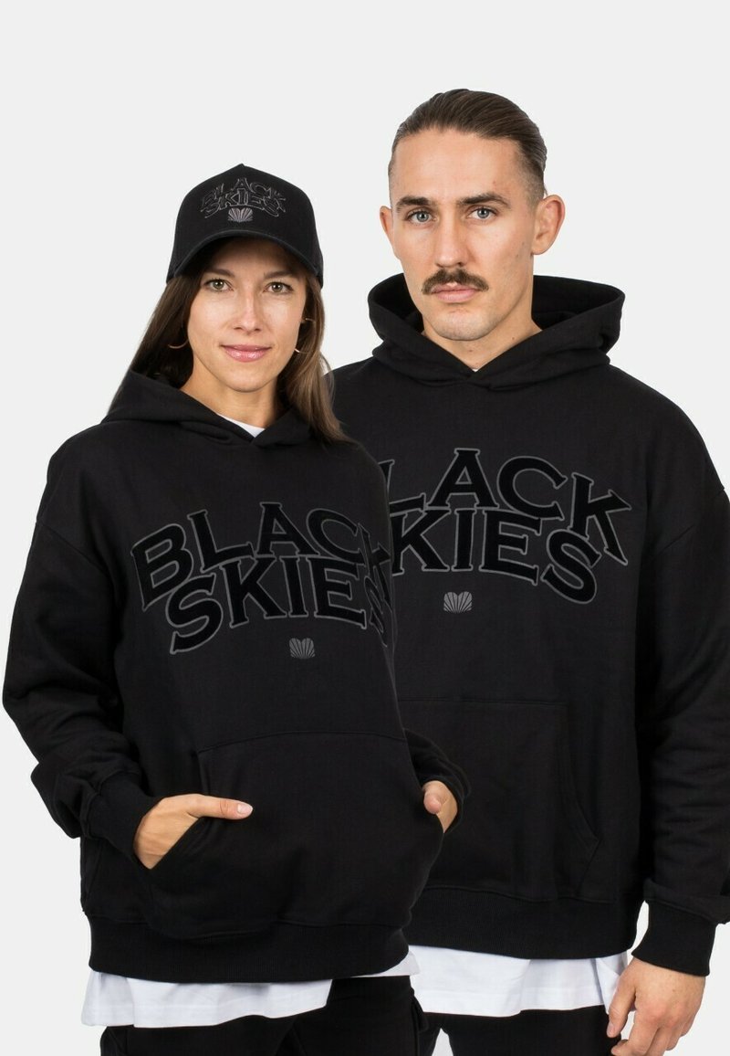 Black hoodies with "BLACK SKIES" lettering, featuring kangaroo pockets and ribbed cuffs. A matching black cap completes the look.