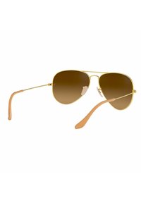 Occhiali da sole aviator dorati con lenti a sfumatura marrone. Montatura metallica sottile con morbidi gommini beige. Naselli regolabili per il massimo comfort.