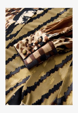 Pruuni ja musta mustriga kangas, millel on tekstuuriga tunne. Omab kraega disaini, millel on nupud ja volditud detailid.