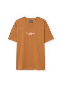 Camiseta de manga corta y cuello redondo en tela de algodón color naranja quemado. Presenta un texto blanco que dice "Éternellement Jeunes" en la parte frontal.