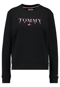 Černá mikina z bavlny s kulatým výstřihem, žebrovanými manžetami a růžovým nápisem "TOMMY JEANS" na přední straně s malým akcentem v podobě vlajky.