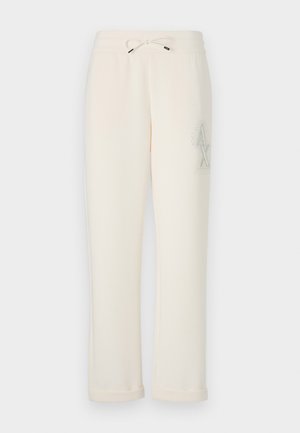 Calças de treino de cor creme feitas de material suave. Apresentam uma cintura elástica com cordão e um logótipo decorativo na lateral.