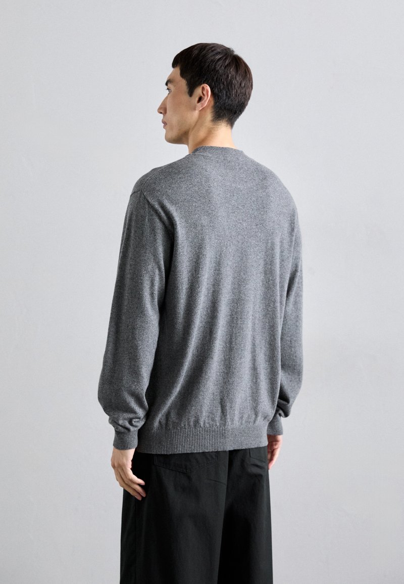 Grauer gestrickter Pullover mit langen Ärmeln, Rundhalsausschnitt, gerippten Bündchen und Saum. Glatte Textur, lässige Passform und schlichtes Design.