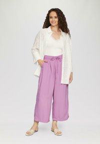 Chemise blanche en broderie anglaise, débardeur en dentelle crème, pantalon large lavande avec cordon de serrage, et sandales beiges à lanières. Textures lisses, coupe décontractée.