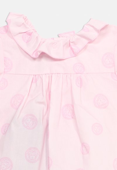 Tessuto rosa chiaro con colletto arricciato e motivo ripetuto di teste delicate di Medusa in una tonalità di rosa leggermente più scura.