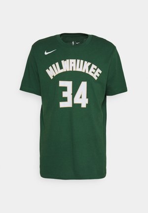 Zaļš kokvilnas T-krekls ar uzrakstu "MILWAUKEE" un "34" baltā krāsā ar zelta kontūru. Nike logo uz kreisā krūšu apgabala, ar apaļu kakla izgriezumu.