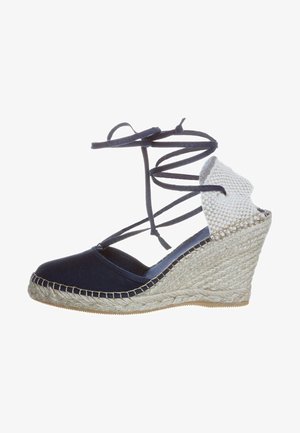 Navy fabric wedge espadrille with ankle ties, woven jute wedge, smooth upper, and contrasting textured detail on the heel.
