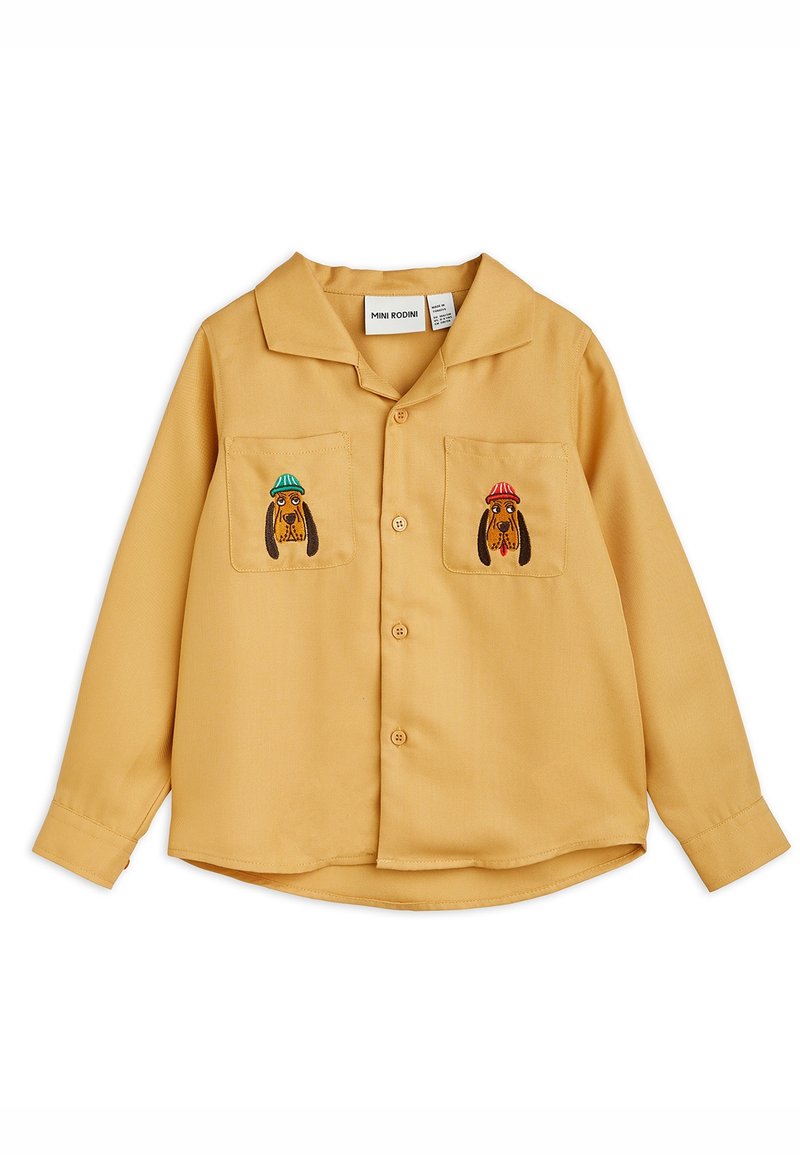 Chemise boutonnée jaune moutarde avec deux poches poitrine, chacune brodée d'un chien portant un chapeau de couleur différente.