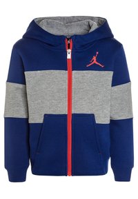 Sweat à zip bleu marine et gris avec des accents rouges, poche kangourou et un logo noir sur la poitrine. Fabriqué en tissu doux mélangé. Style hoodie.