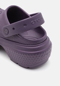 Sandales en crocs violettes avec un design à plateforme, un dessus texturé, une sangle ajustable et des perforations pour une meilleure respirabilité.