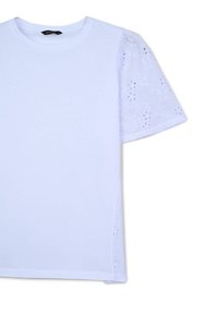 T-shirt bianco con parte anteriore liscia e maniche corte in pizzo ricamato testurizzato con fori floreali, che offre un elemento di design a contrasto.