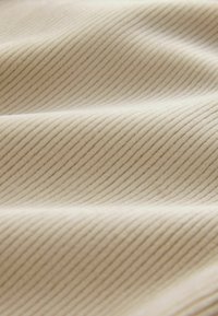 Tejfehér szövet finom bordás textúrával, váltakozó világos és sötét csíkokkal, lágy és sima megjelenéssel.