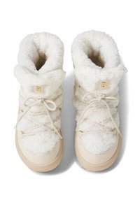 Białe botki wyłożone futerkiem o miękkiej fakturze, z sznurowaniem, złotymi akcentami i zaokrąglonymi podeszwami. Górna część posiada wywinięty mankiet.