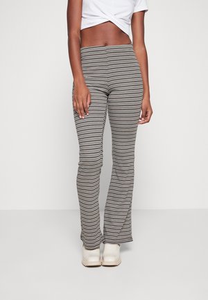 Randiga utsvängda leggings i svart, gräddfärgad och taupe, med en åtsittande silhuett och slätt tyg. Matchas med ljusa skor.