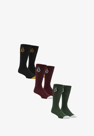 Drei Paar kniehohe Socken: schwarz mit gelben Akzenten, burgunderrot und grün mit weißen Zehen; alle haben ein strukturiertes, geripptes Design.