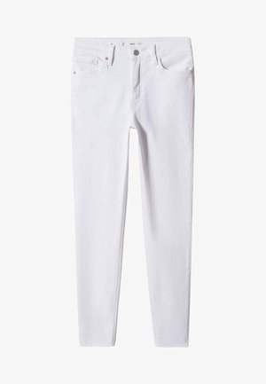 Osoba nosząca czarną skórzaną kurtkę, czarno-białą paskowaną koszulę, białe obcisłe dżinsy i srebrne baleriny stojąca na betonowej podłodze.