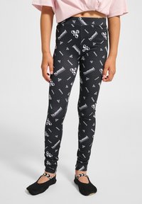 Svarta leggings med ett upprepande vitt "hummel"-logotyp och mönster, med en figurnära design och elastiskt tyg. Matchade med svarta skor.