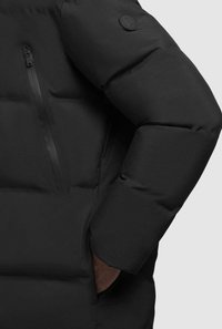Giacca a vento nera con tasca con zip e toppa rotonda sul maniche; texture liscia con sezioni trapuntate per l'isolamento.