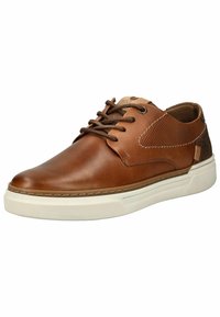 Zapatilla de piel marrón con un acabado suave, suela de goma blanca y detalles perforados en el lateral, presentando cordones marrones y un parche con el logo.