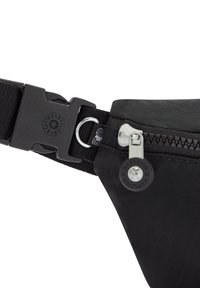 Zwarte nylon heuptas met een rits, verstelbare band, plastic gesp en een ronde logo-accent. Textuur oppervlak met minimale details.