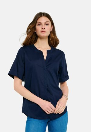Navy blue short-sleeve shirt with a round neckline, button placket, and a slight hemline curve. Smooth texture and tailored fit.
