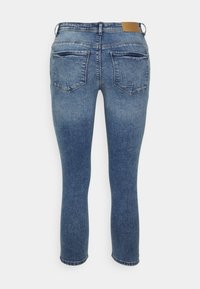 Jeans de denim ajustados em azul médio com um efeito desbotado, dois bolsos traseiros e um remendo de couro castanho na cintura.