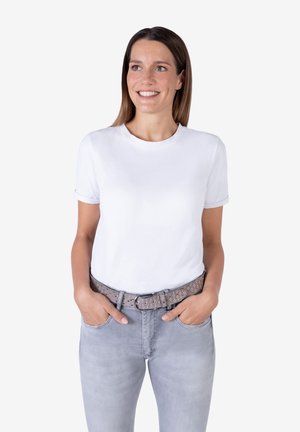 White cotton t-shirt with rolled sleeves, paired with light gray jeans and a patterned gray belt featuring metallic accents.