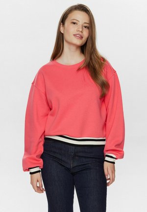 Koraal kleurige pullover sweatshirt met lange mouwen, geribde zwart-wit gestreepte manchetten en een ronde halslijn. Gedragen met donkere jeans.