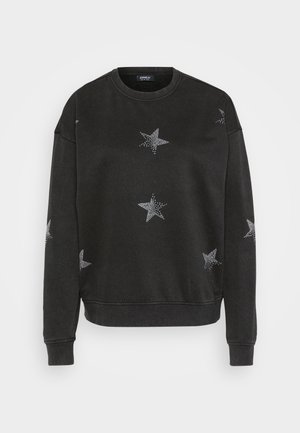 Crna dukserica s uzorcima srebrnih zvijezda, okruglim izrezom i rebrastim manžetama. Izrađena od mekanog tekstilnog materijala s opuštenim krojem.