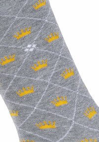 Szare skarpetki z powtarzającymi się motywami żółtych koron, z teksturowanym wzorem i białymi liniami geometrycznymi na tkaninie.