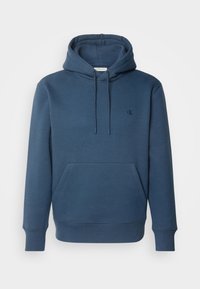 Kapuzensweatshirt in Dunkelblau, aus weichem Material gefertigt. Mit einer Front-Känguru-Tasche, gerippten Bündchen und einem kleinen Logo auf der Brust.