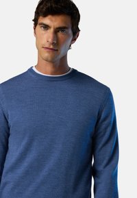 Maglione blu realizzato in materiale morbido, con scollo rotondo e maniche lunghe. Texture liscia con colore uniforme e dettagli minimali.